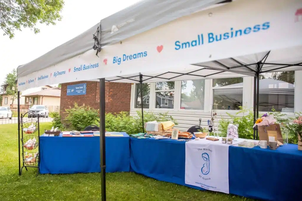 Handmade goods on blue-draped tables under a Small Business Big Dreams canopy